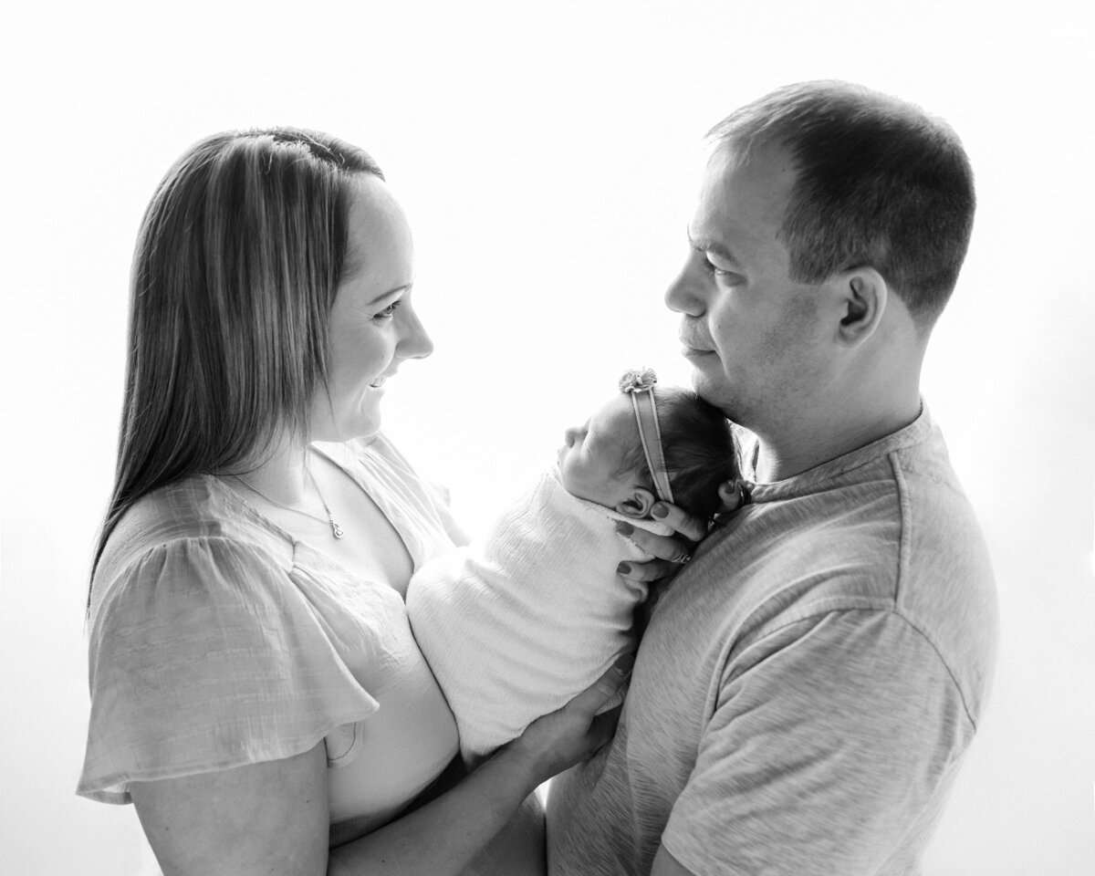 mom and dad holding newborn baby girl for studio portraits