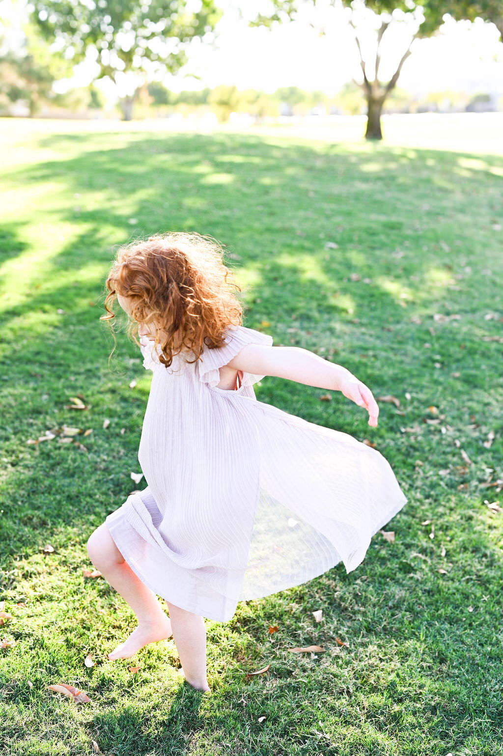 A small girl in a dress dancing in a field.