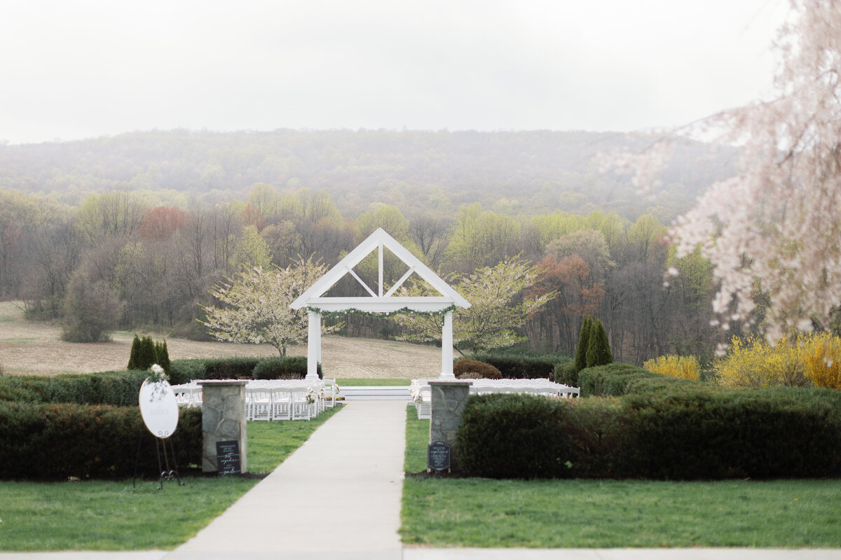 White arbor framed by rolling mountains set for outdoor wedding ceremony at Springfield Manor.