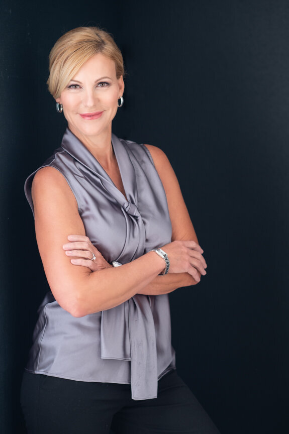 a very professional polished corporate branding photo of a woman in a grey silk blouse and folded arms