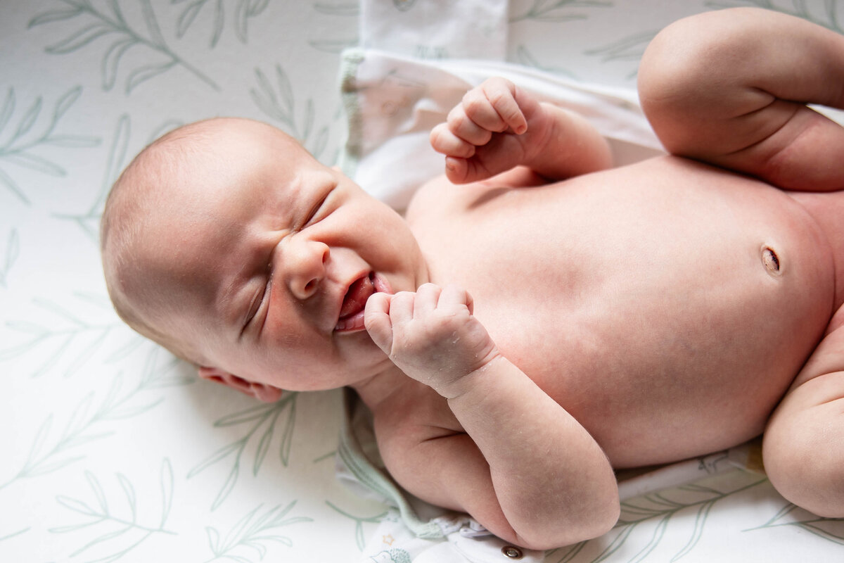 Newborn baby smiling while his diaper is changed