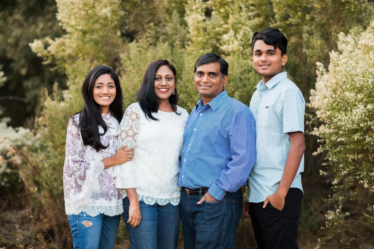 Parents pose for family photos with their young adult children amongst the green shrubbery along a hiking trail