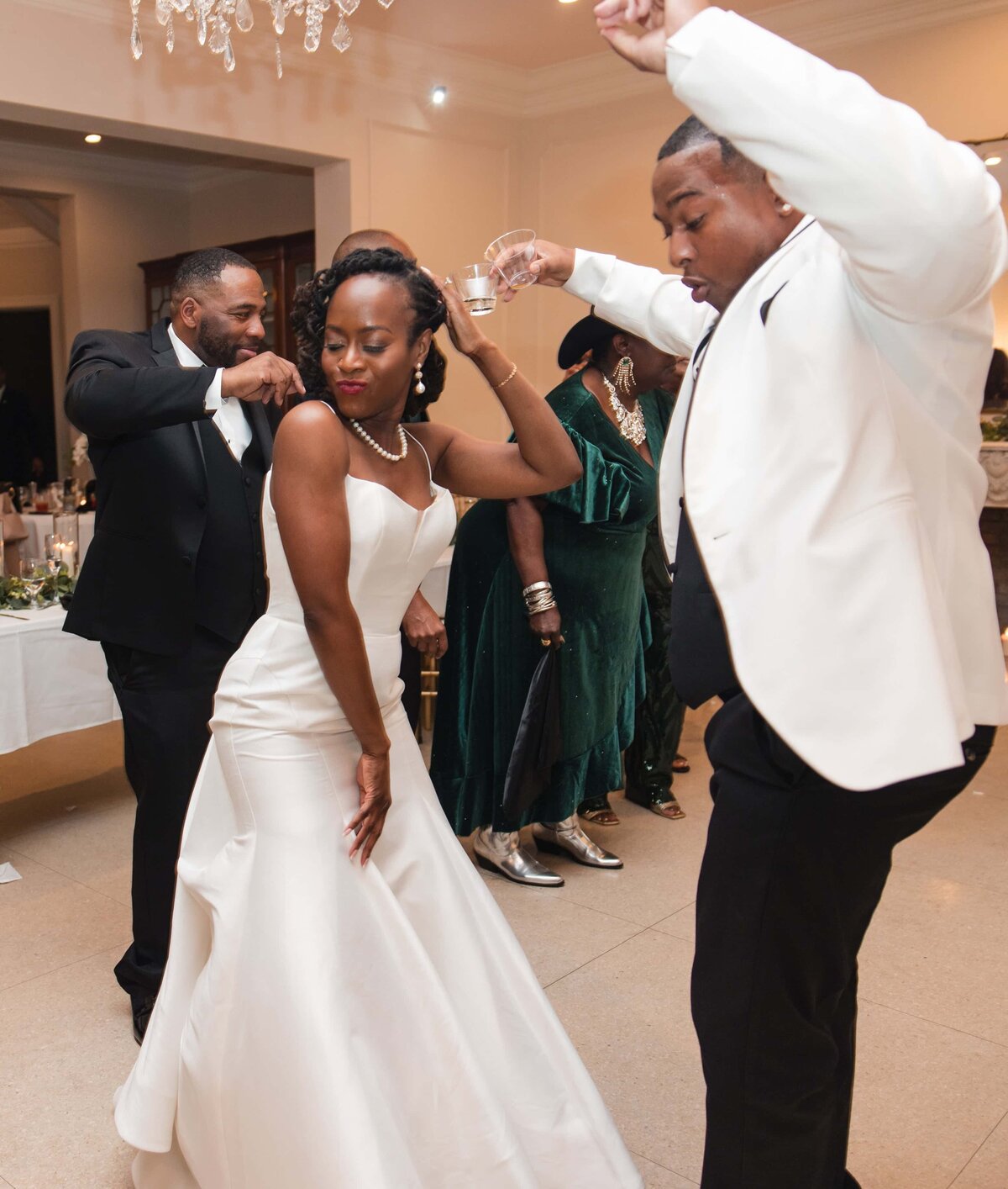 he bride and groom share a fun and energetic dance during their wedding reception at Azaleana Manor in Orange Park, Florida. The bride, in a strapless satin gown, dances confidently beside her groom, who is dressed in a sharp white jacket and black pants. Surrounded by guests and joyful energy, the couple celebrates their love on the dance floor. Captured by Heartful Films, a Jacksonville wedding photographer and videographer specializing in candid, high-energy wedding moments.