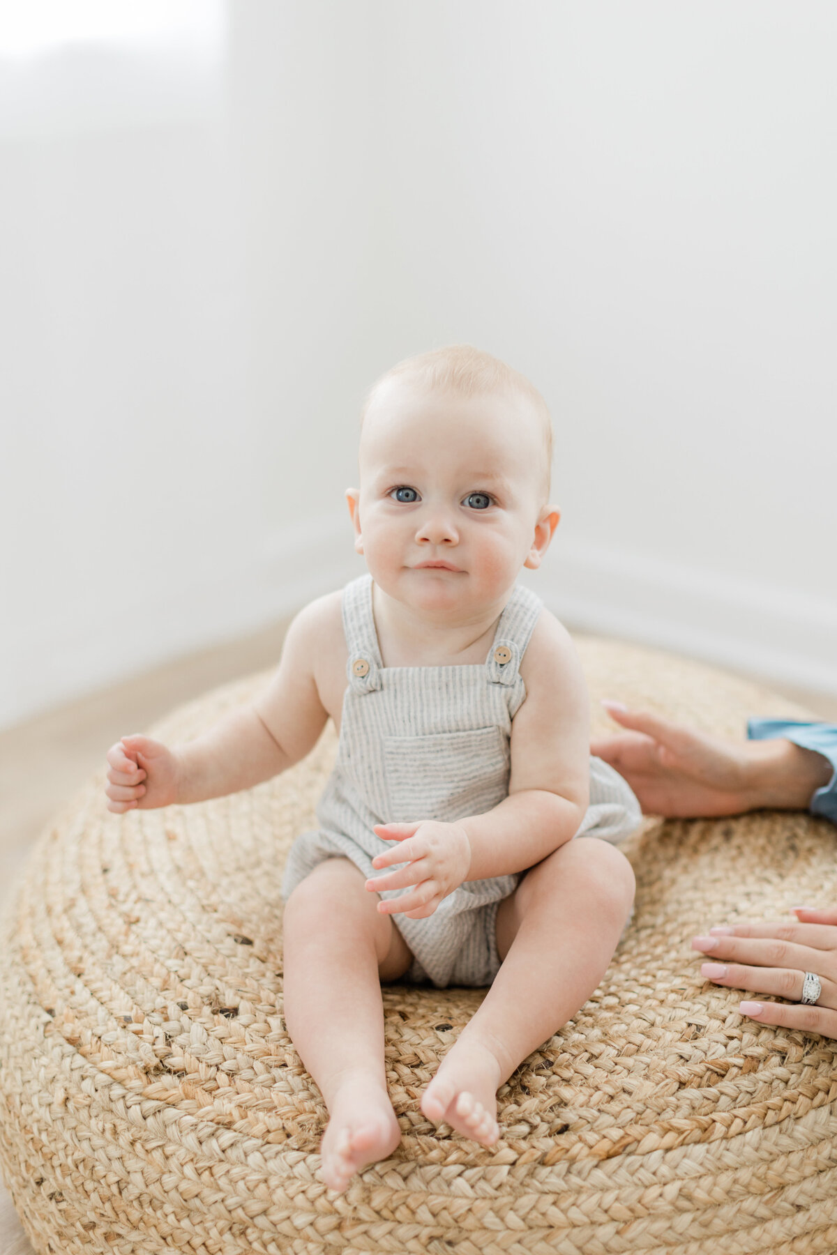 9 month old baby boy sitting on a jute poof photographed by Philadelphia Portrait Photographer Tara Federico