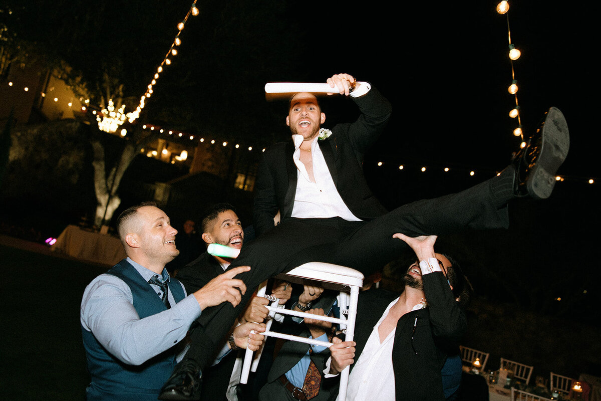groom on chair being lifted at bella collina wedding florida​