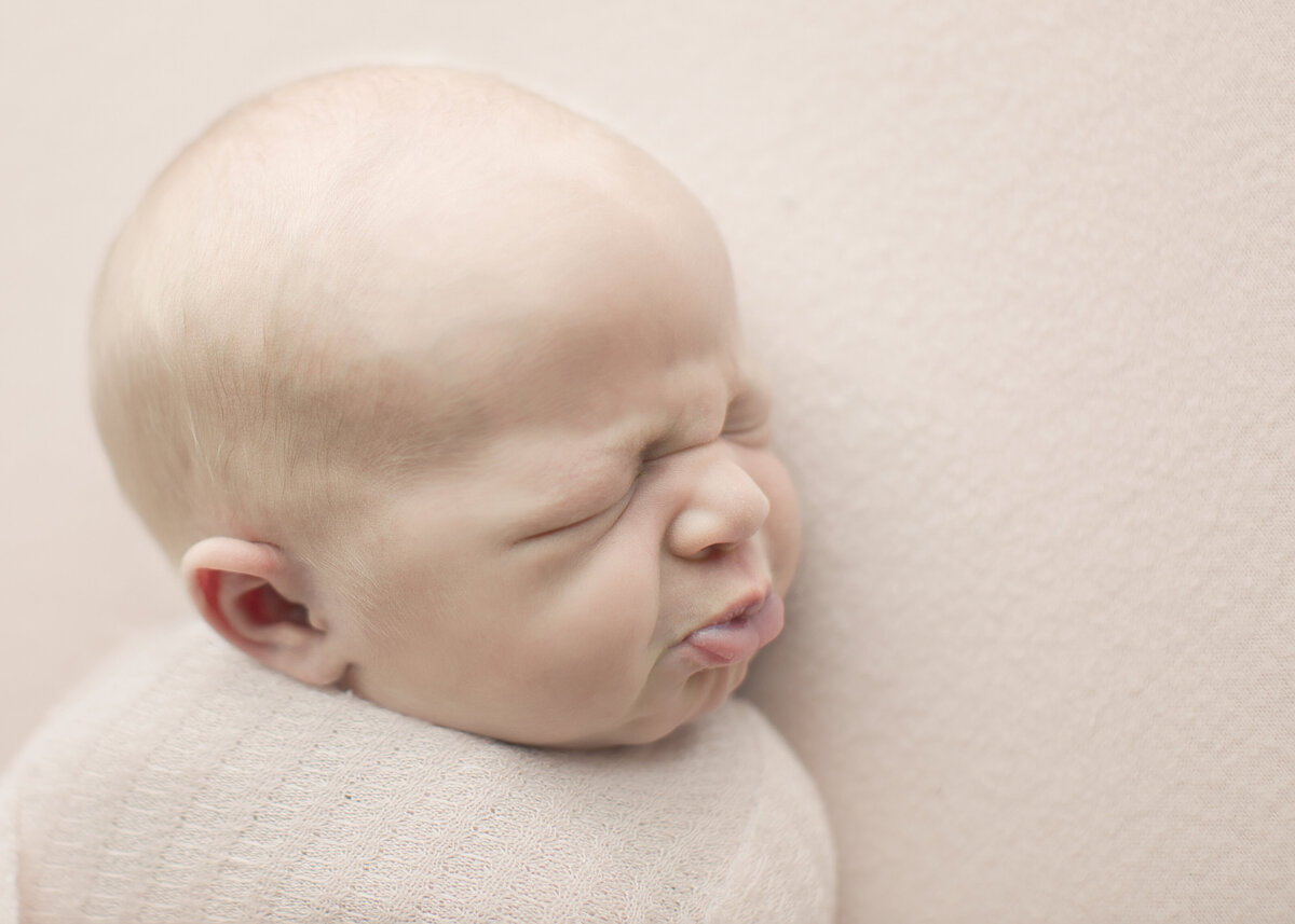 newborn baby boy makes funny face for picture