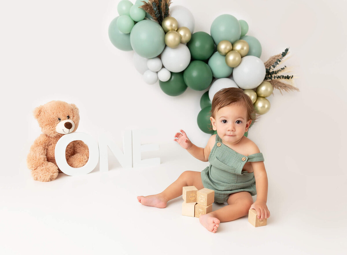Baby boy sage and green ballon garland cake smash baby playing with blogs