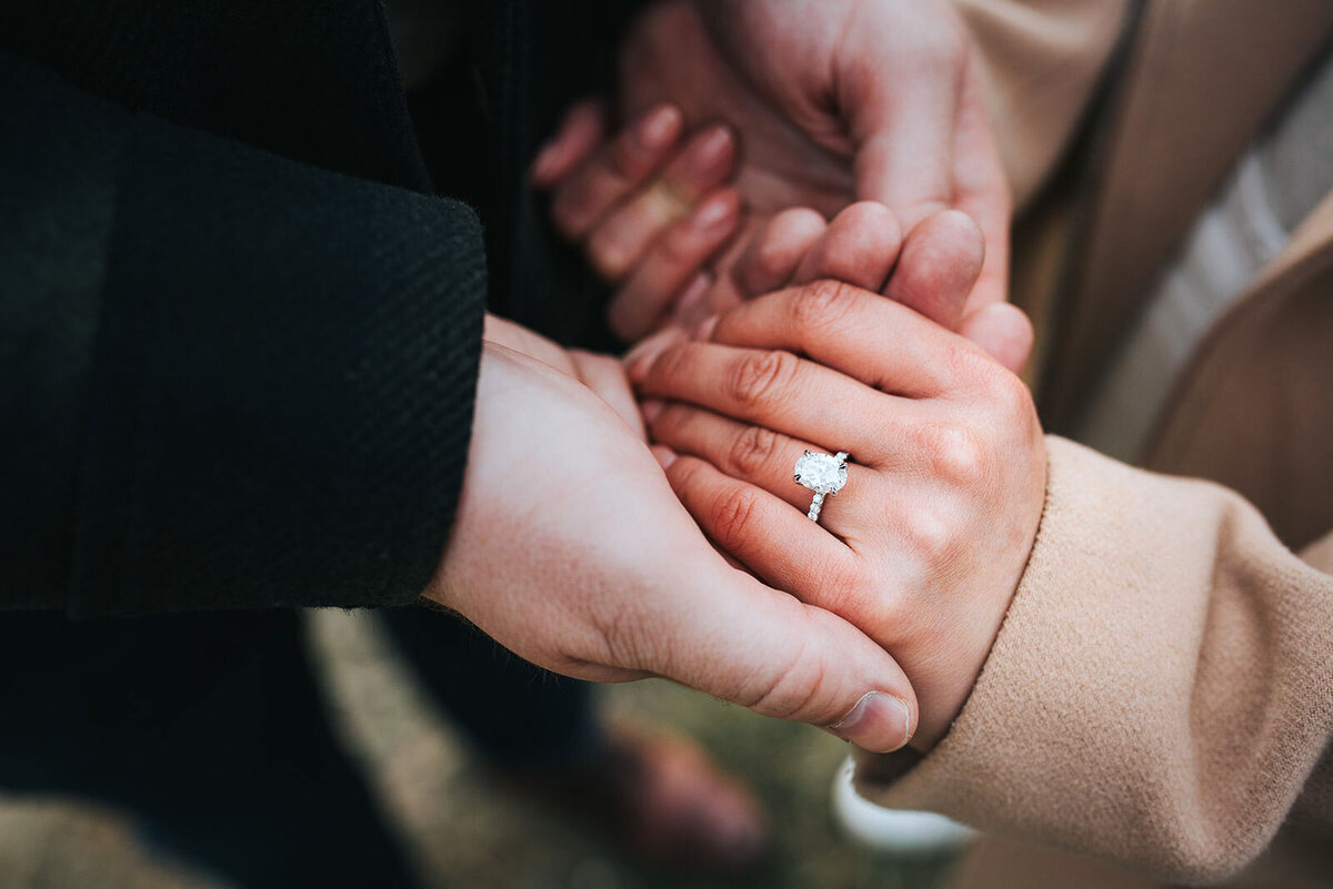 closeup of couple holding hands with diamond engagement ring at killington mountain proposal
