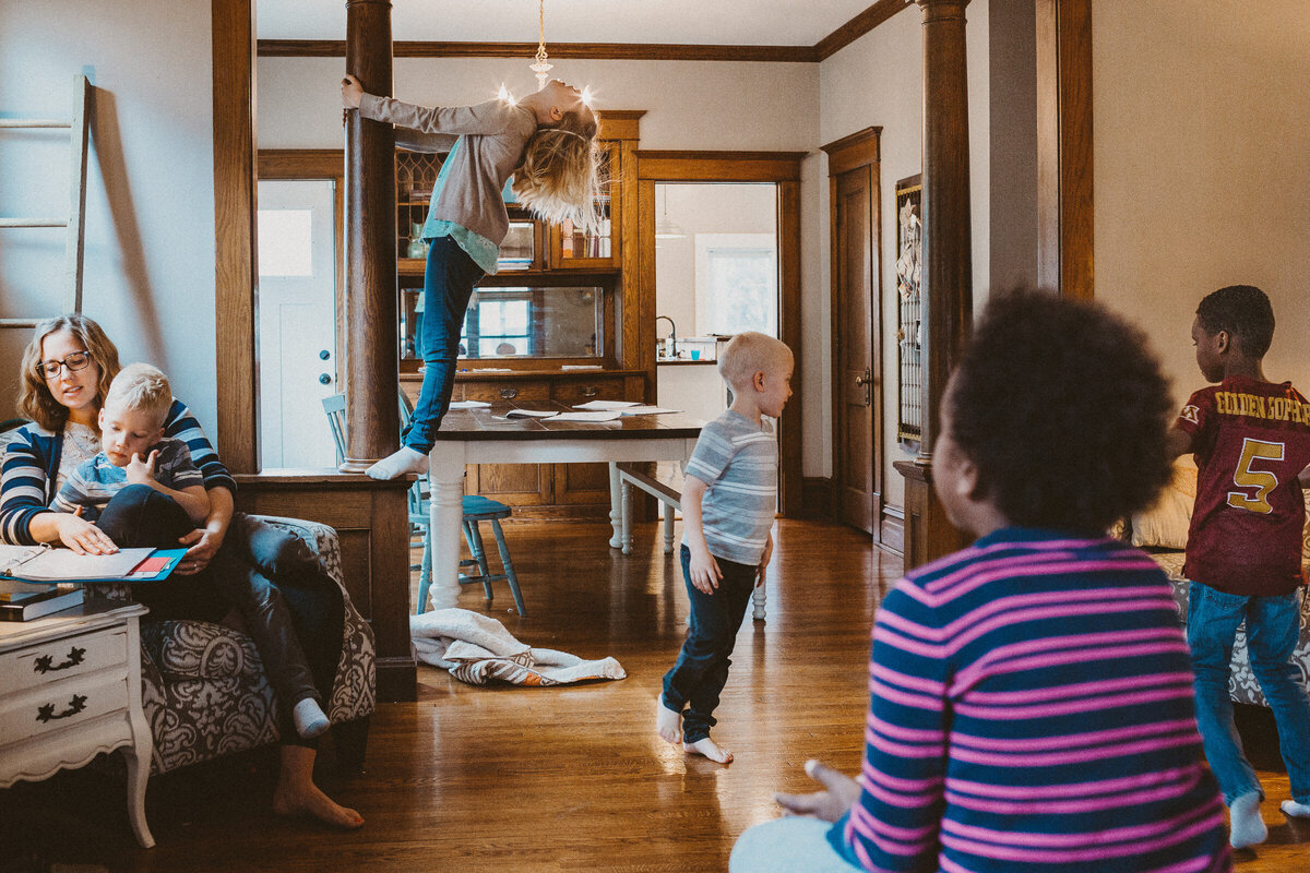 homeschool family dances around the living room as mother reads to the kids