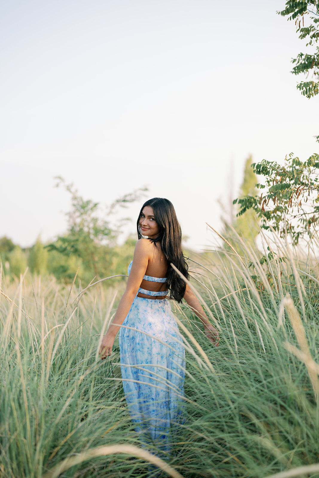 High school senior walking through tall beach grass at Lake Michigan during her South Haven senior session.