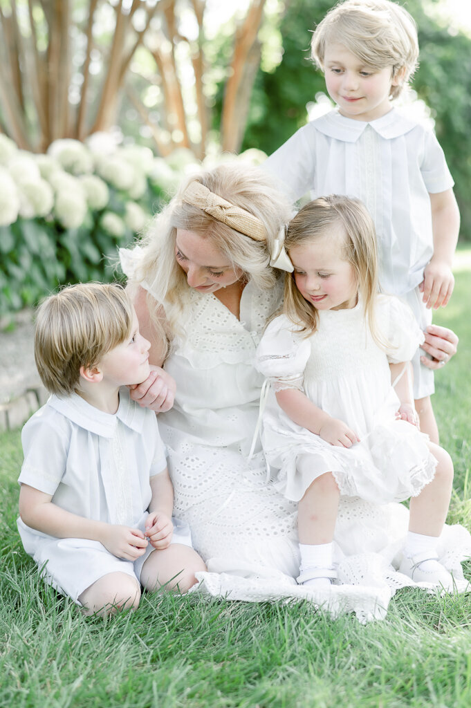 Mother plays with her children sitting in the grass