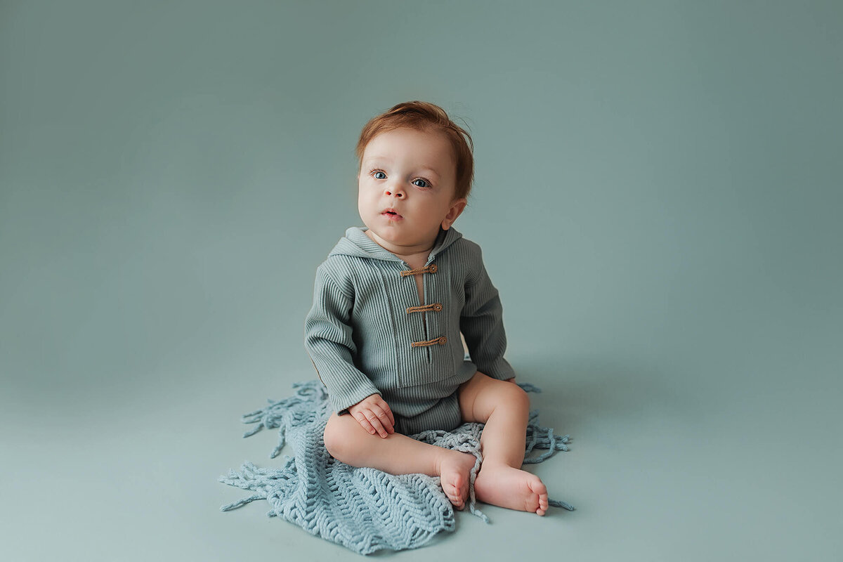 Baby boy wearing a light blue romper for his milestone session in Minnesota.