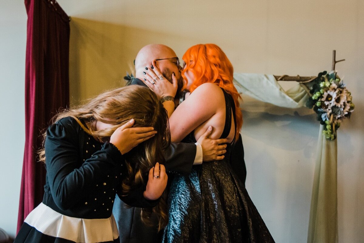 Bride and Groom in a black gown and black Suit kiss at their wedding ceremony.