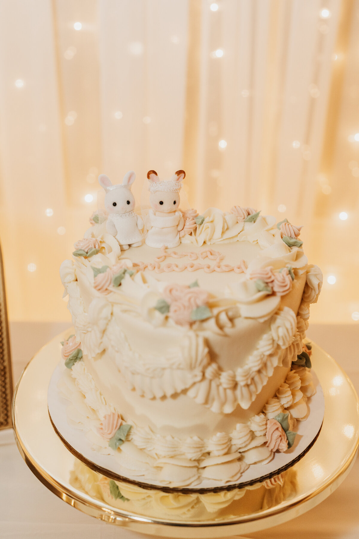 A heart shaped wedding cake with small cake toppers on it 