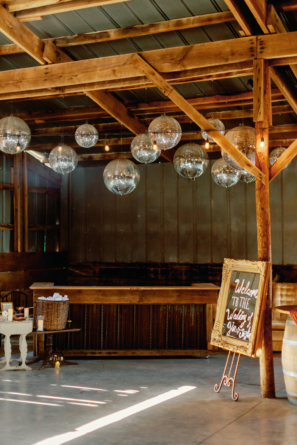 Rustic barn wedding venue decorated with hanging disco balls and twinkling lights for modern reception vibe.