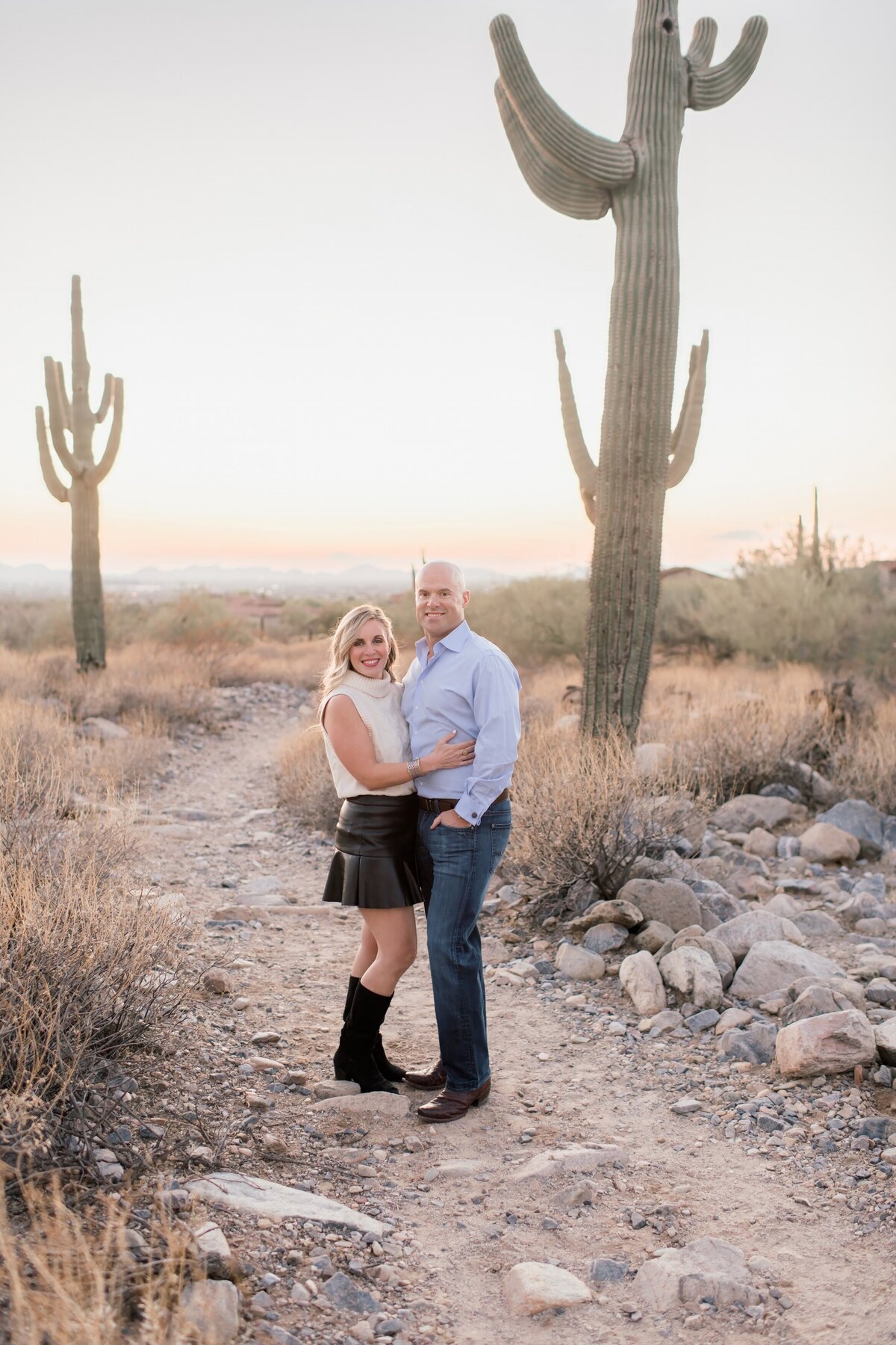 parents in a pose holding on to each other smiling at the camera in the arizona desert