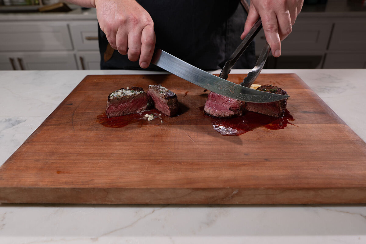 A person slicing two small steaks 