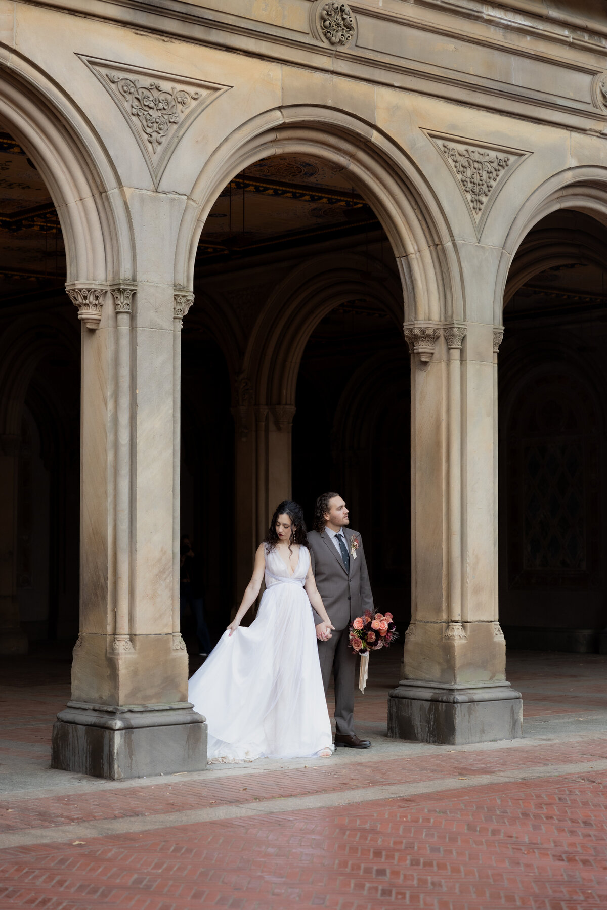 The couple sharing a tender moment beneath Central Park’s beautiful stone arches.