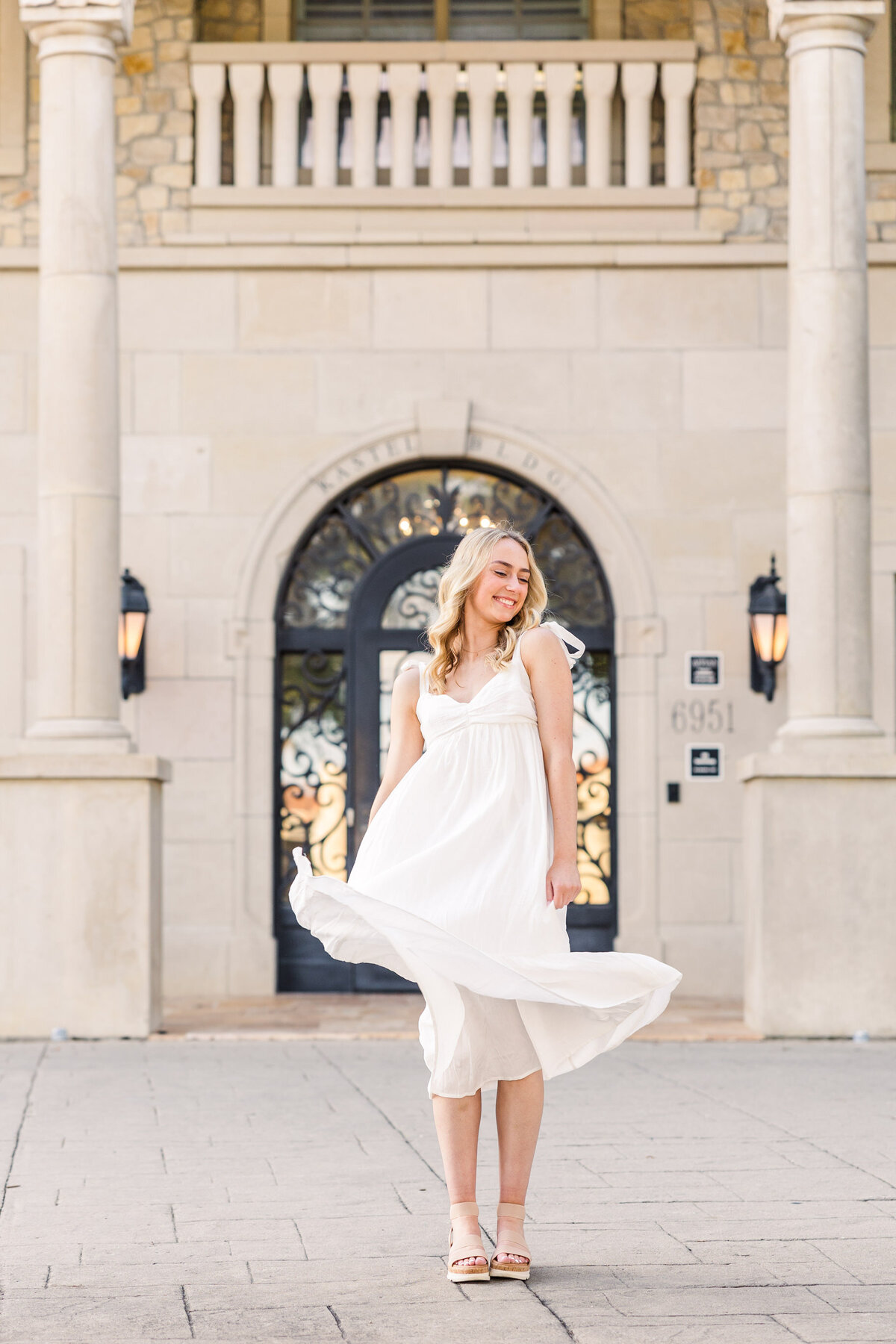 A graceful senior poses in front of the iconic stone architecture at Adriatica Village in McKinney, TX. Captured by Jennifer Lynn Photography, a trusted DFW senior photographer offering natural and classic portraits throughout North Texas.