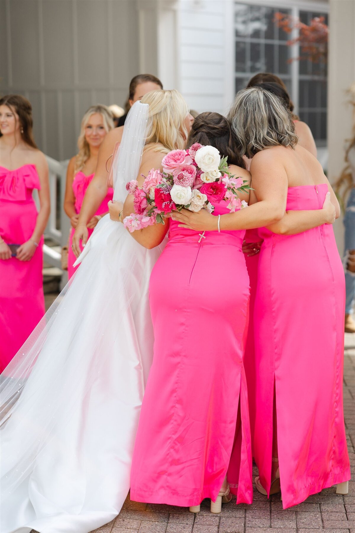 Bridesmaids wearing hot pink lily pulitzer gowns hugging the bride before the ceremony