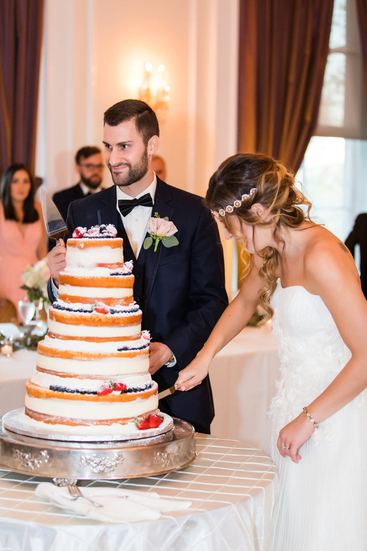 groom laughing as they cut wedding cake at university club