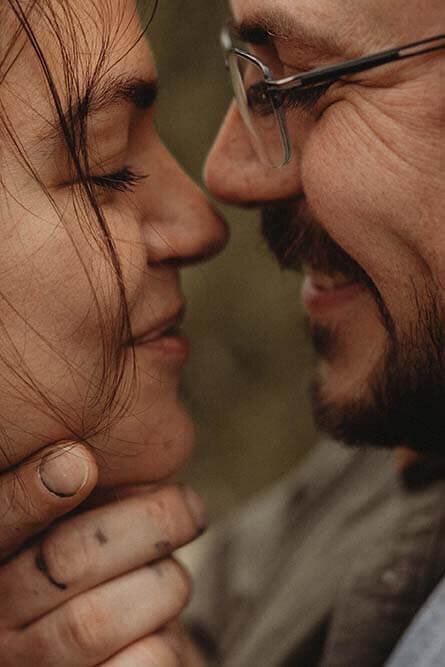 A husband lovingly holds his wife super close with their noses barely touching