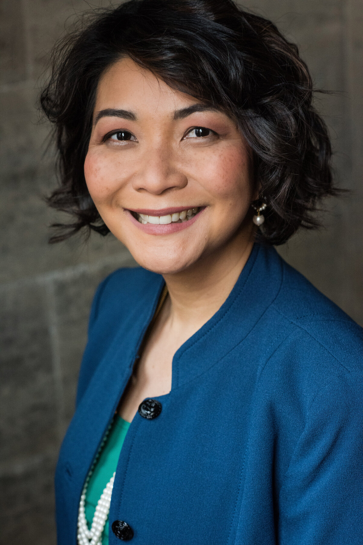 A person in a blue blazer looking to the side and smiling