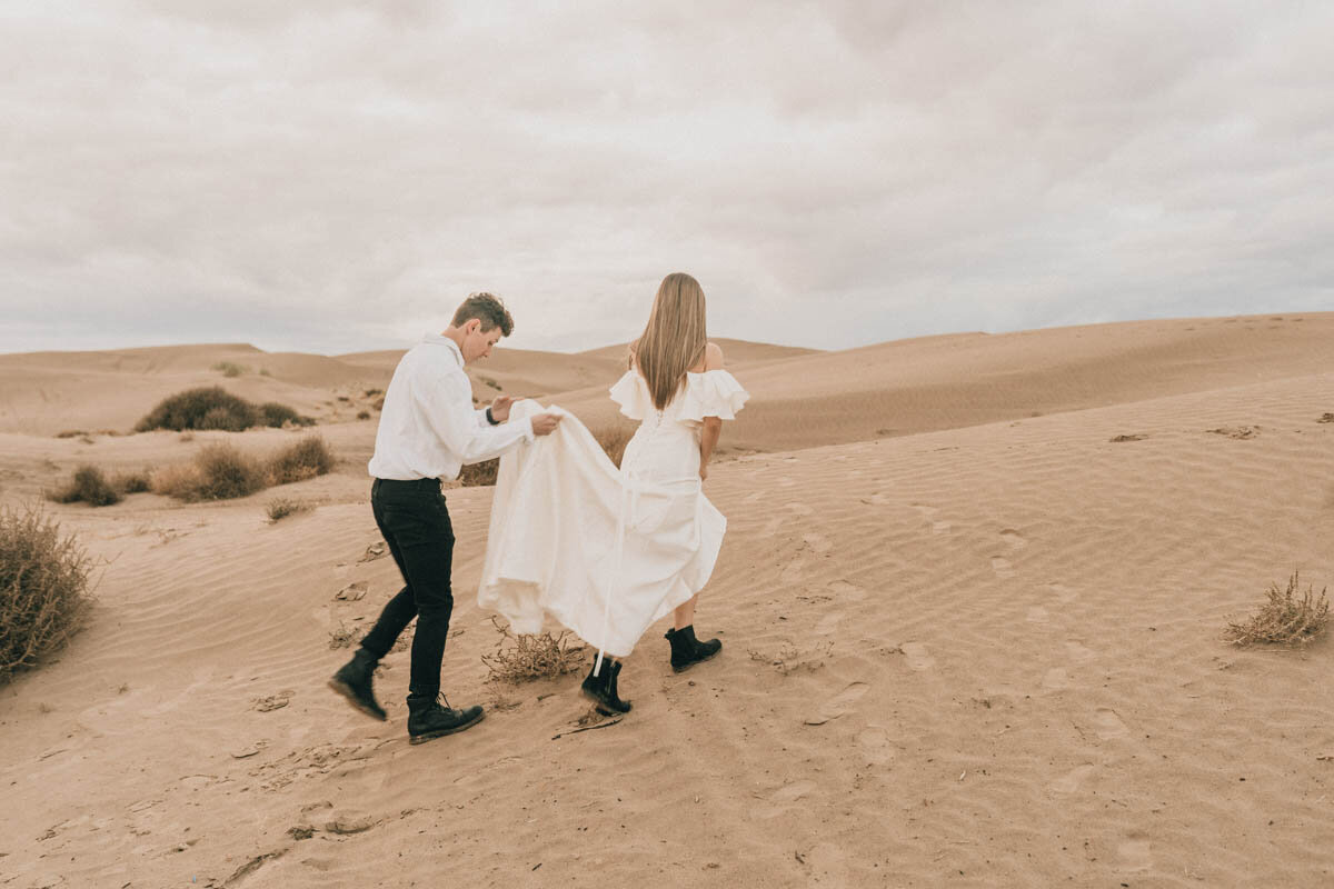 groom lifting the train of his bride's dress