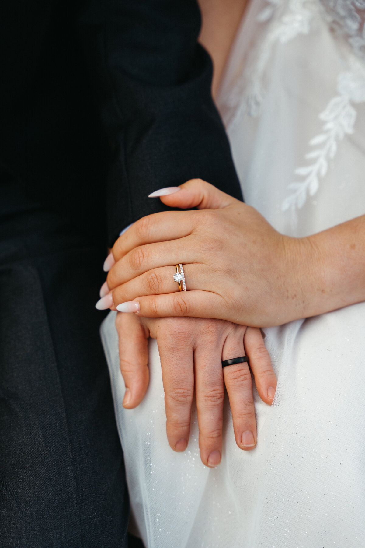 Close-up of wedding rings and hands on bride’s dress