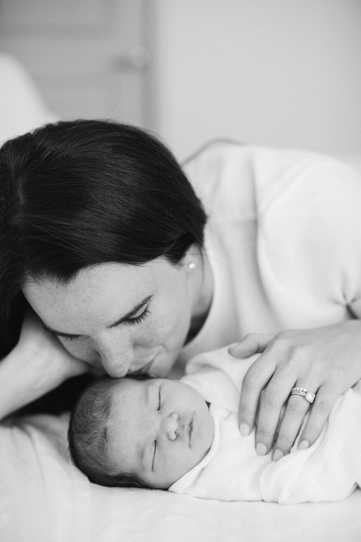 mother kissing baby at home newborn session in New Hampshire