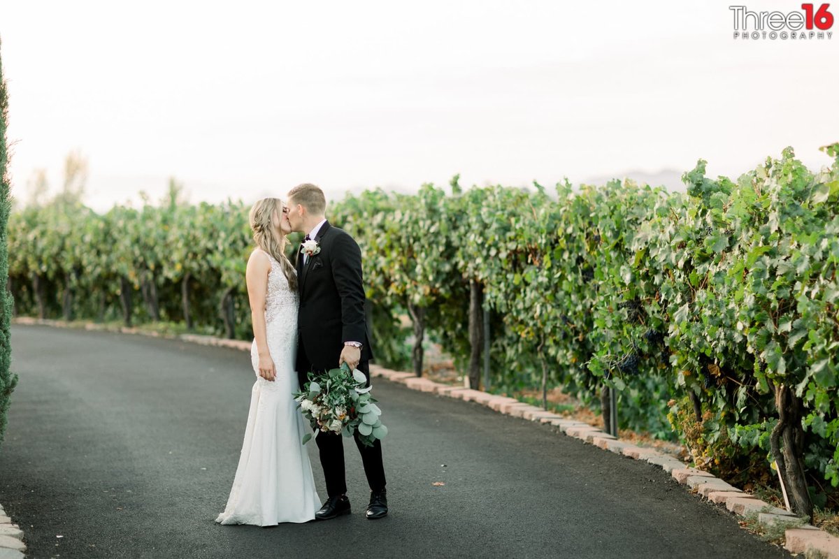 Bride and Groom share a kiss while walking along the winery