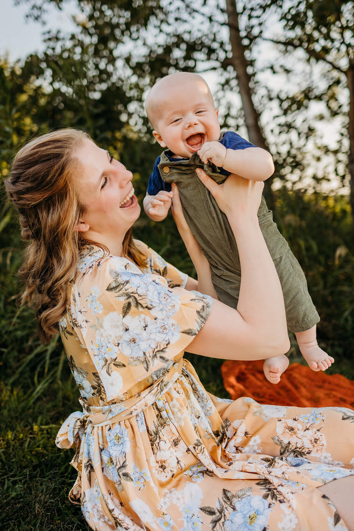 laughing mom in yellow flower dress holding up son, a family photography session