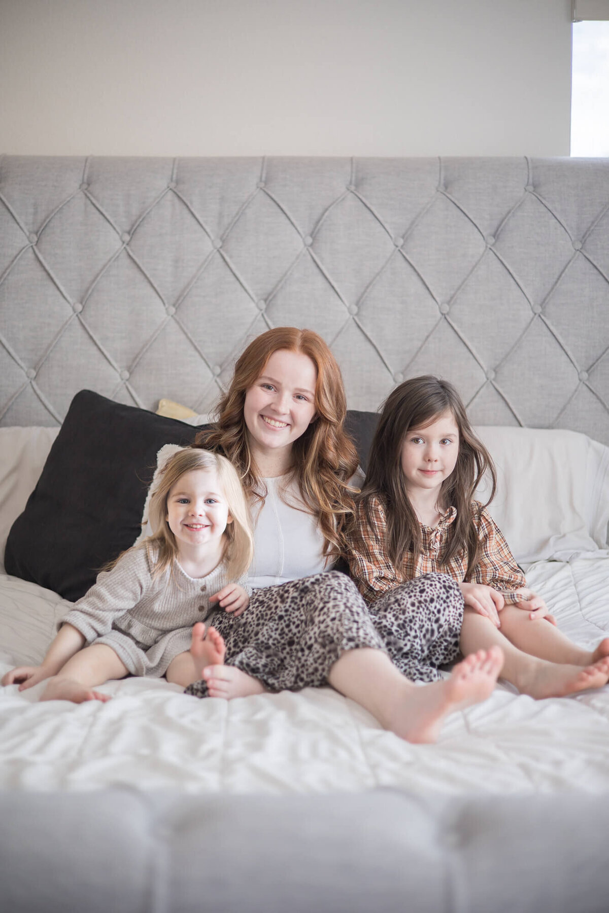 mom and her two small daughters on a bed