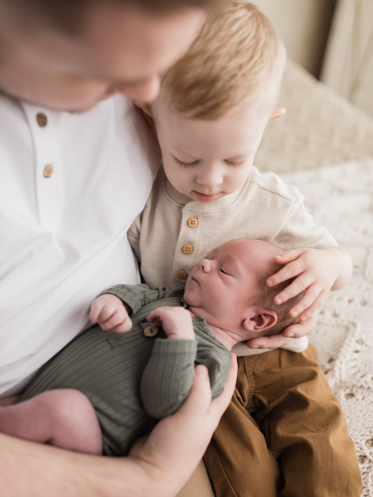 dad and son holding newborn baby boy in green onesie