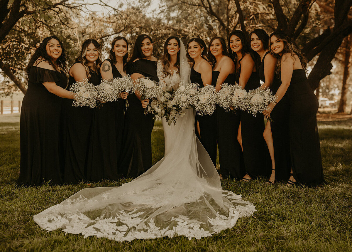 Bride holding her bouquet and wearing her wedding gown with the bride's maid wearing black gown