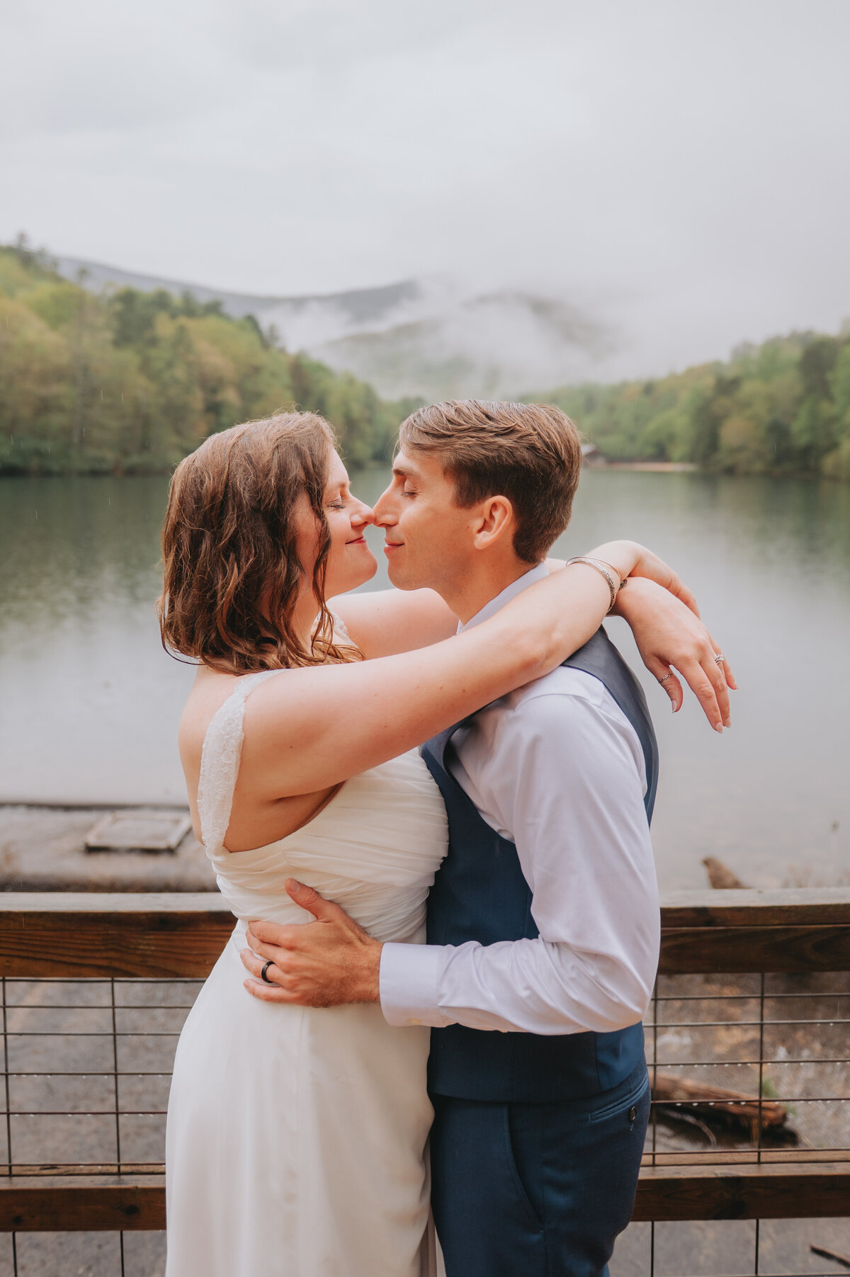 Two people stand nose to nose in front of mountains and a lake