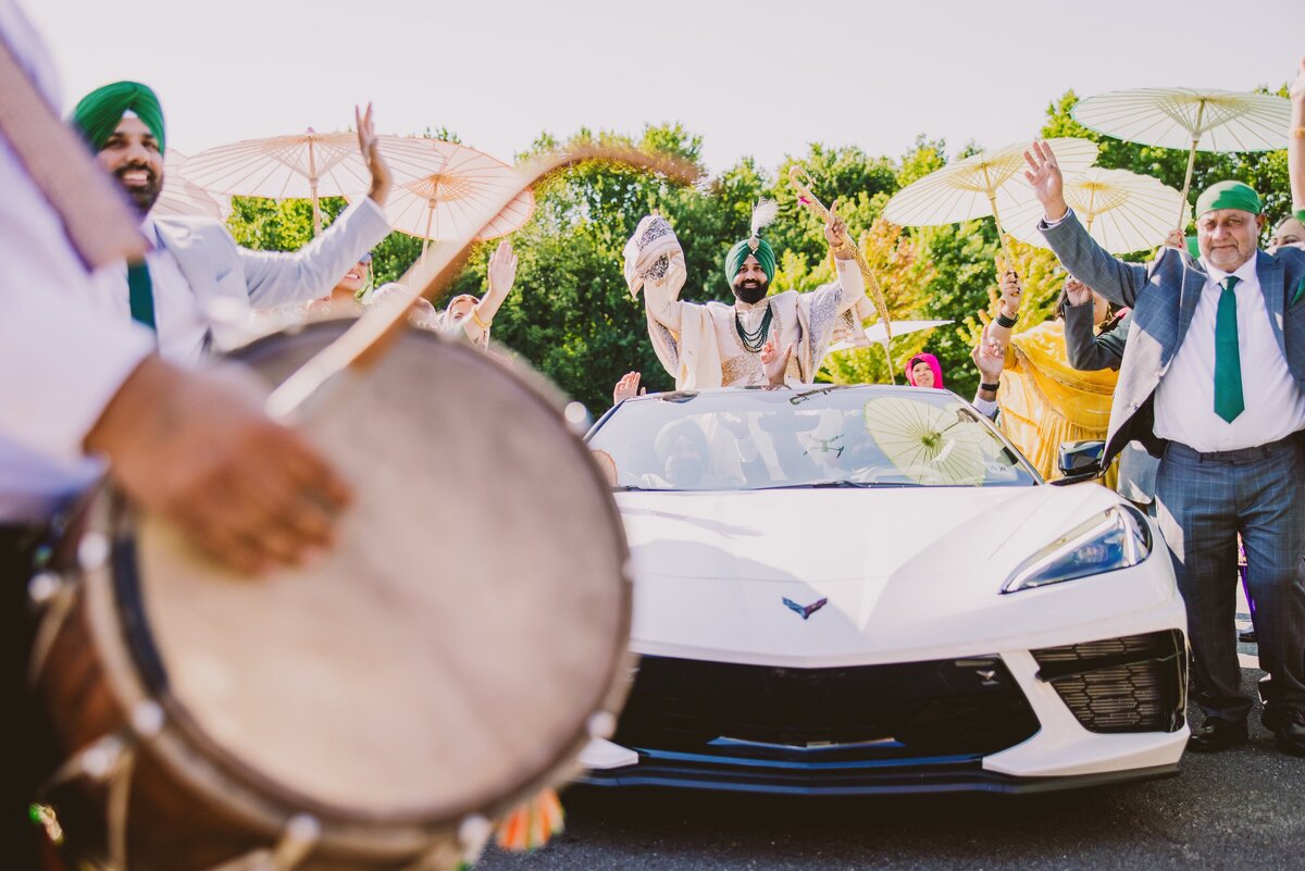Sikh groom dancing to the dhol inside corvette during his baraat 