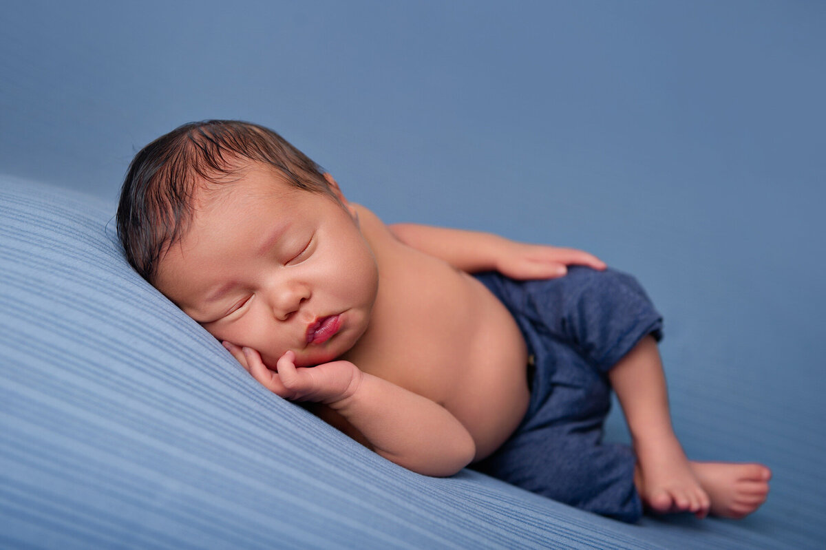 cute baby boy is blue pants relaxed and sleeping