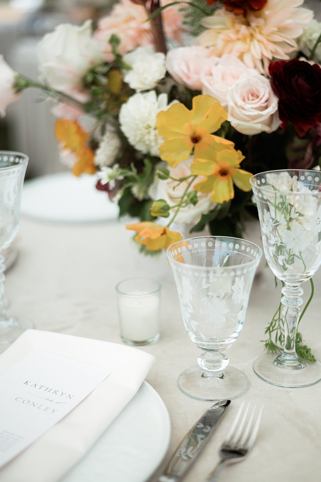 A set table at a wedding, with flowers, glassware, candles, and more.