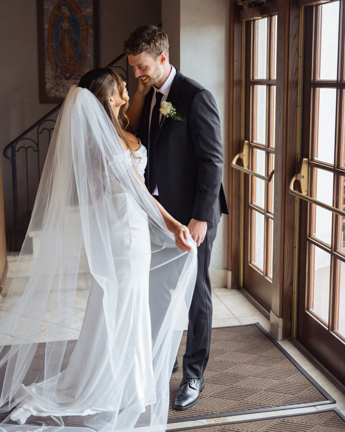 A catholic couple smiles at each other in a romantic portrait at St. Ann's Catholic Church in Nashville Tennessee after their catholic wedding.