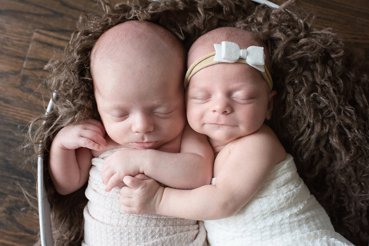 Boy & girl twins cuddling in a basket at their twin newborn photo shoot in Dallas, TX.