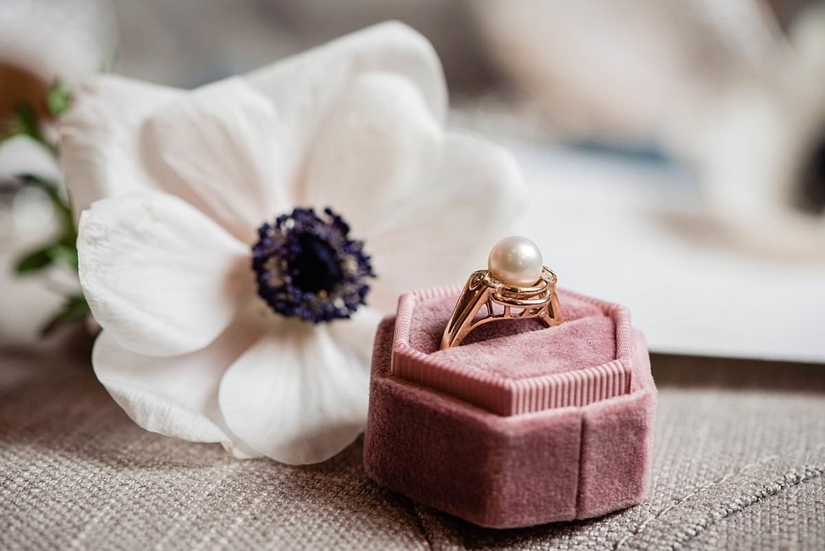 Family heirloom of a vintage pearl ring in a gold setting sitting beside an anemone