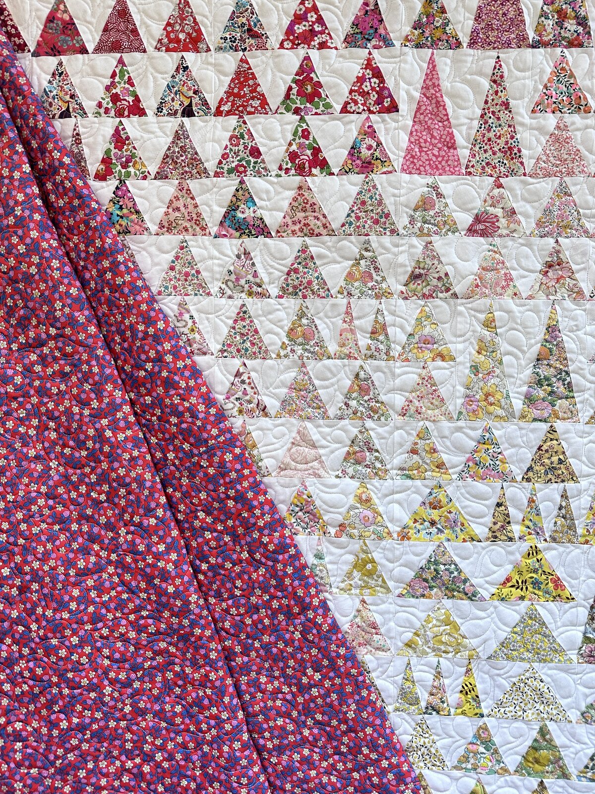Triangle quilt featuring Liberty fabrics features the all-over feather quilting design.