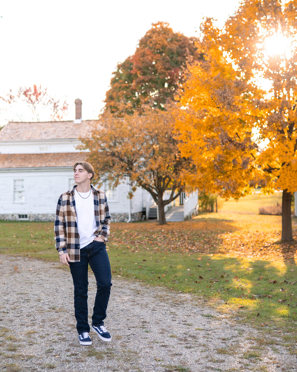 male teenager taking a casual walk on a gravel path with fall golden leaves 