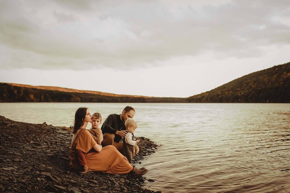A mother holds her son on her lap while her husband and other son play at the water in Canandaigua, NY