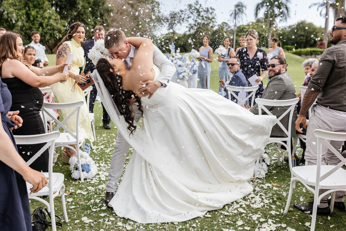 The bridal couple shares a dip-kiss while being showered by confetti. 