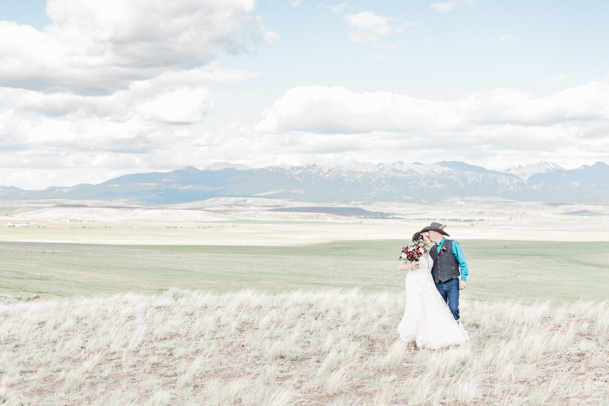 Ranch wedding in Bozeman, MT. Bride and groom kissing in front of the Rocky Mountains