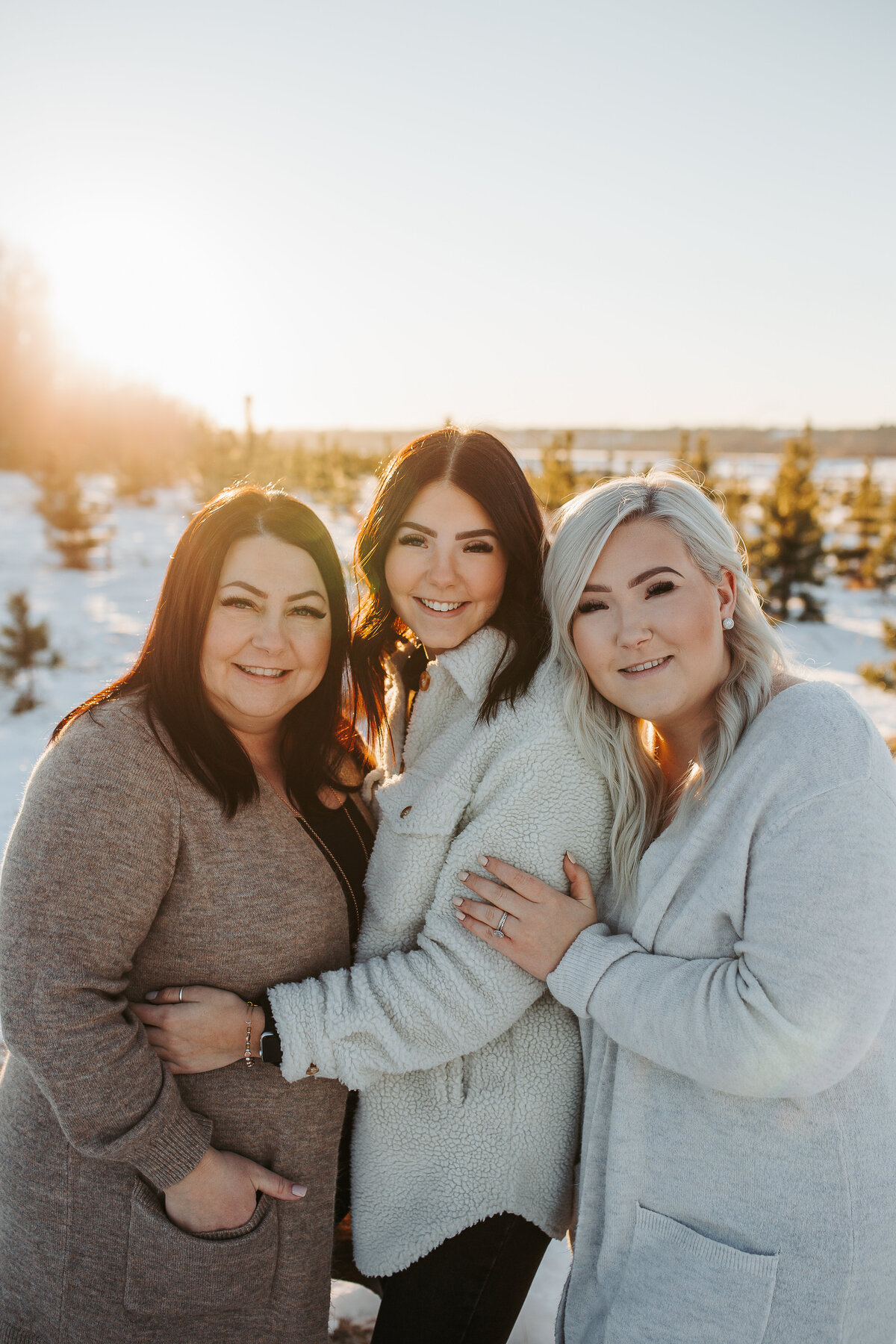 mom and daughters hugging and smiling during a winter sunset