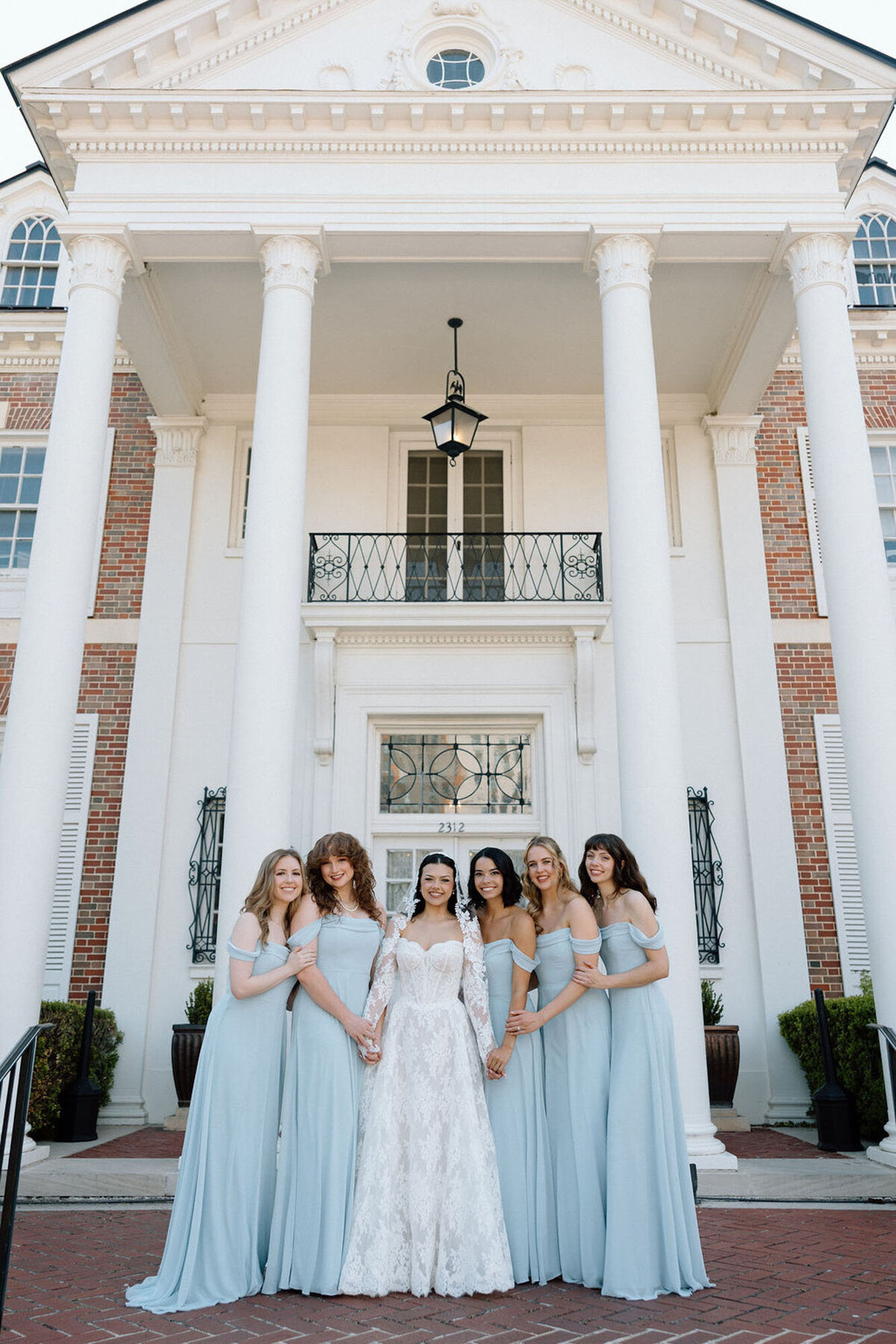Bride and bridesmaids in light blue dresses posing outside