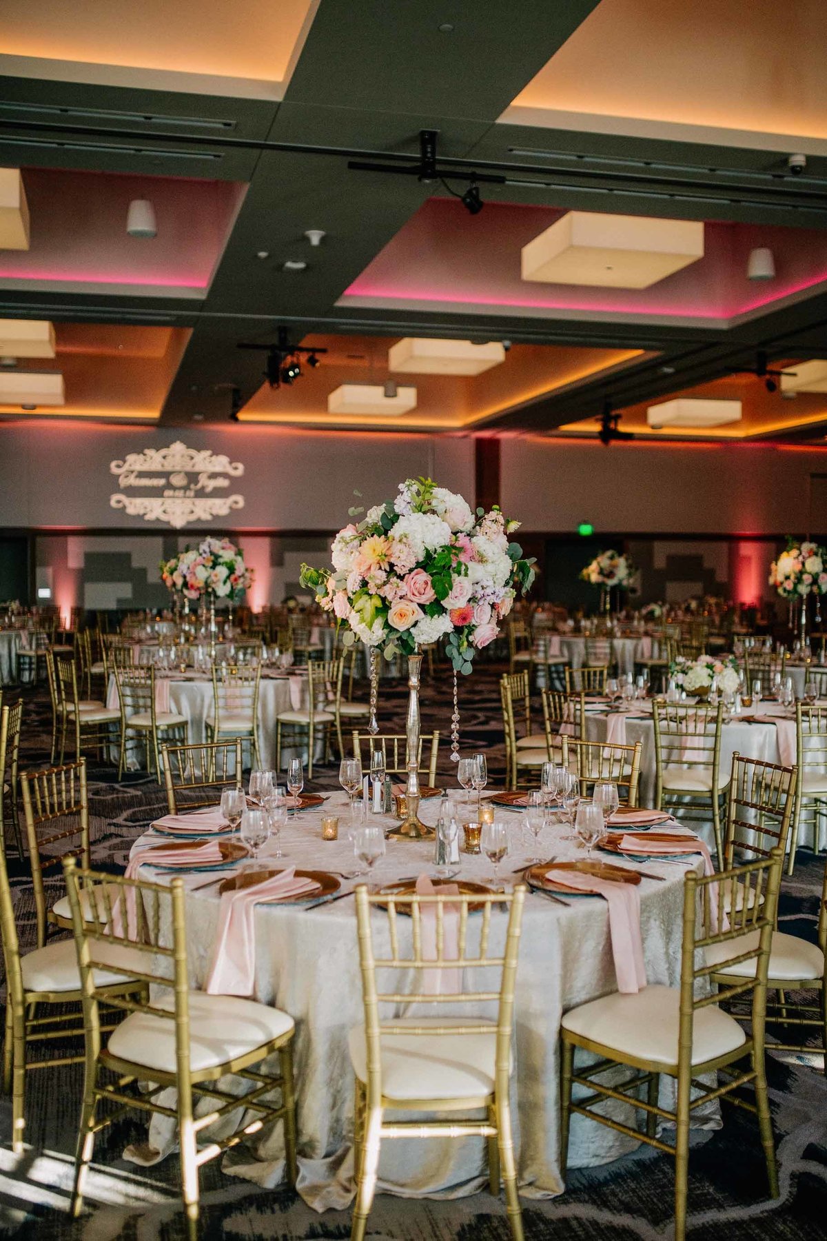 Beautiful tall floral arrangements on round tables with gold chiavari  chairs